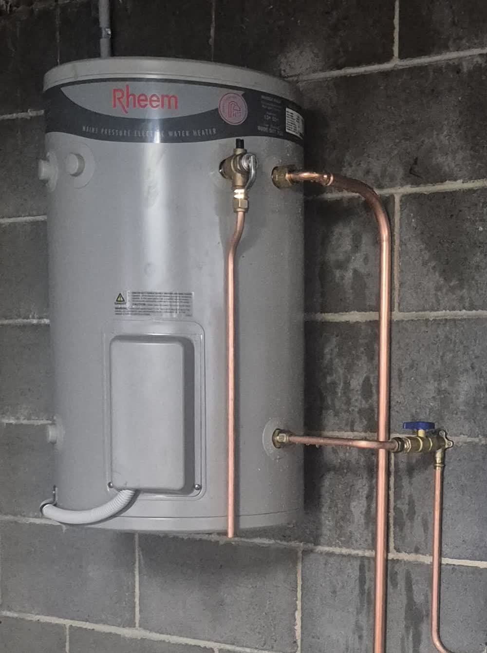 Wall-mounted Rheem mains pressure electric hot water unit with copper pipework
