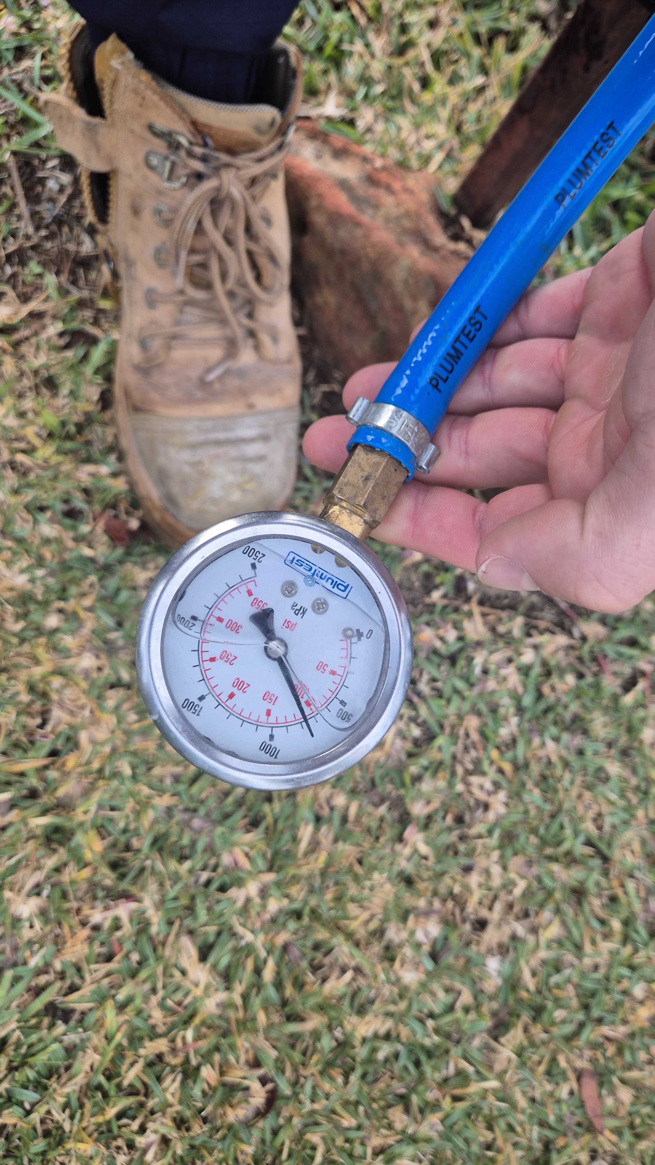 Plumtest pressure test gauge on a blue hose used for leak detection